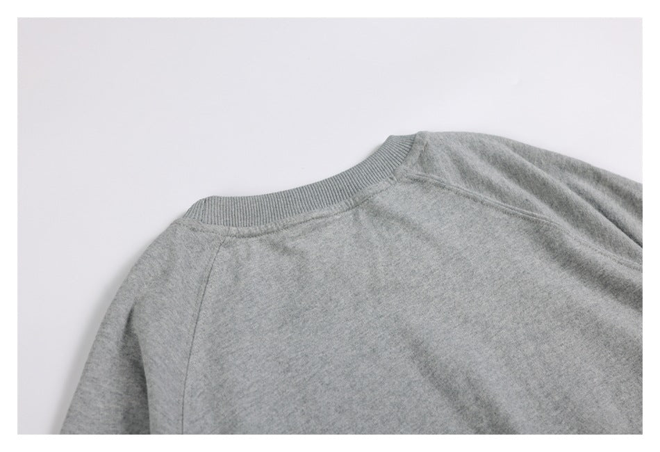 Close-up of the light gray sweatshirt's ribbed crew neckline and shoulder seams.