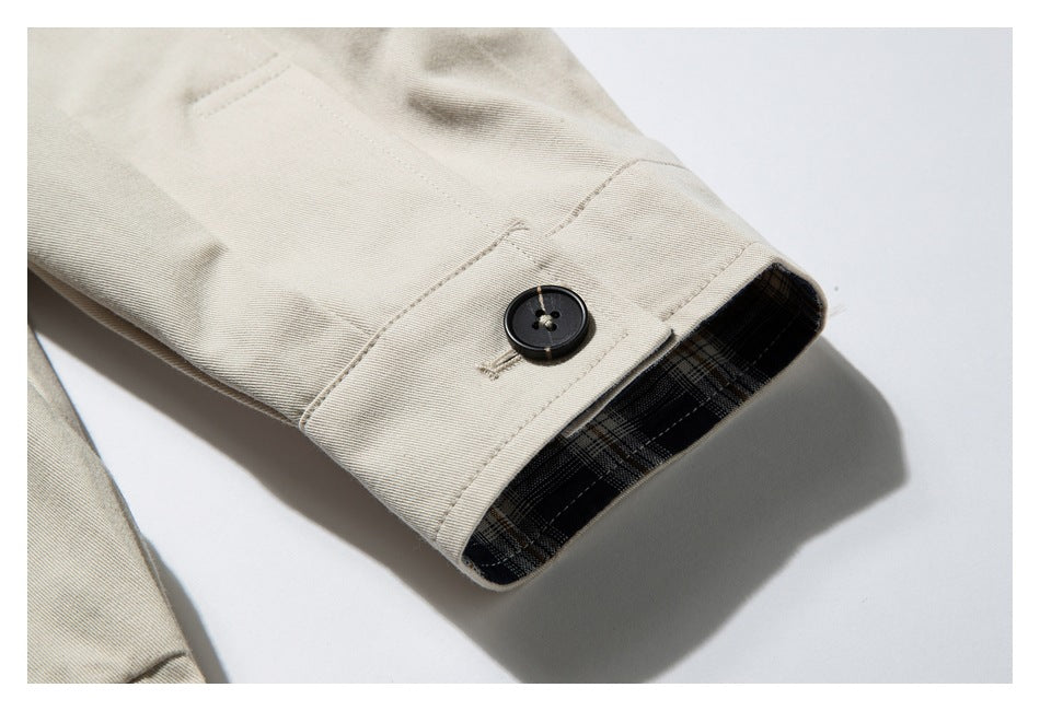 Close-up of a buttoned beige jacket cuff with dark plaid lining.