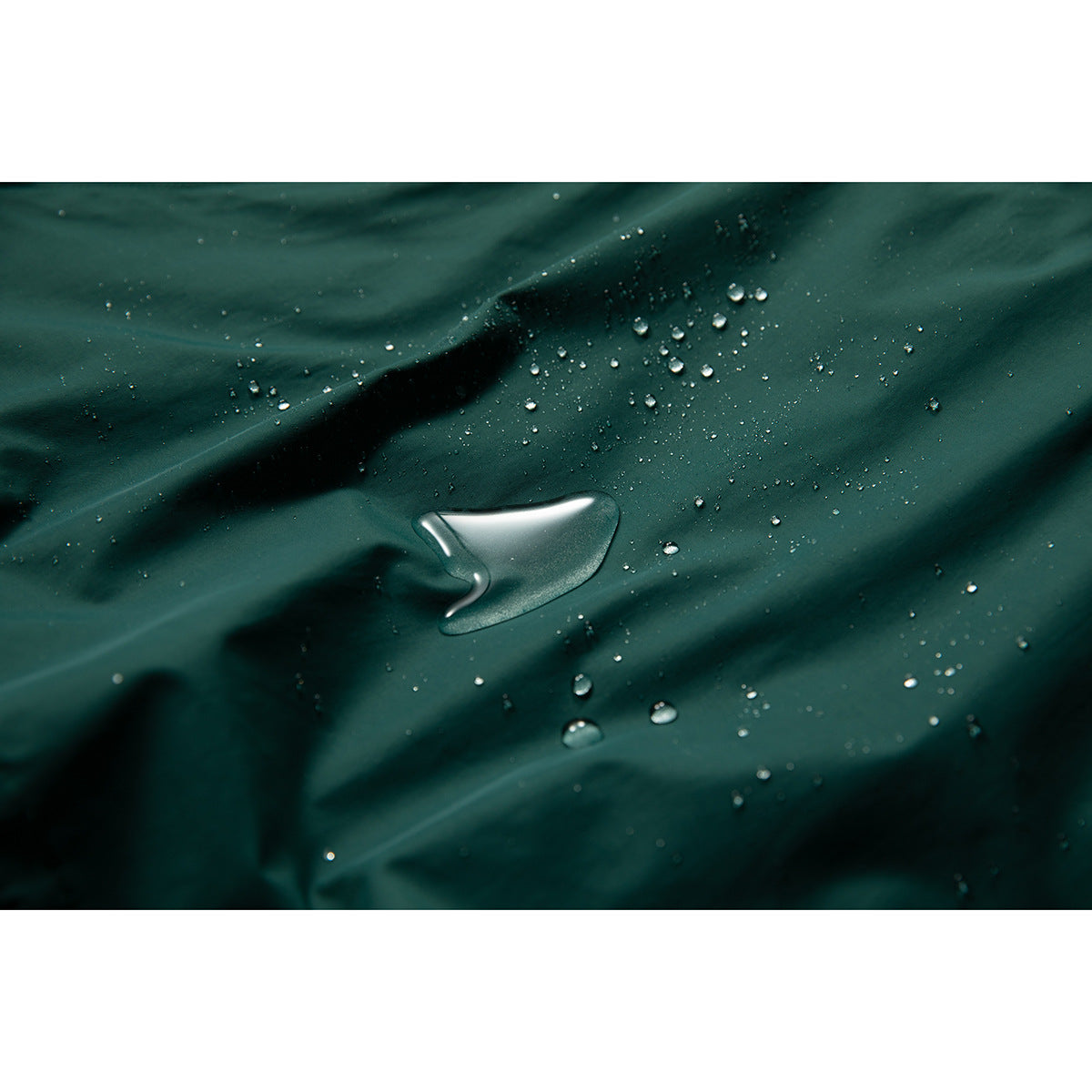 Water droplets bead on the dark teal jacket fabric in a close-up view.