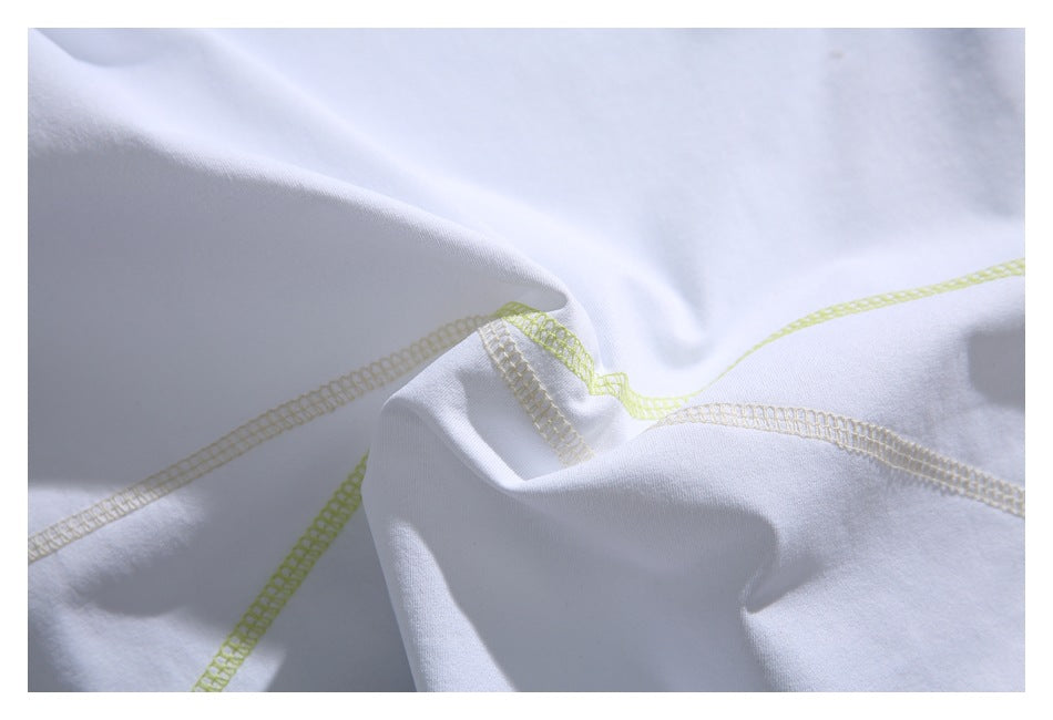 Close-up of pale yellow-green and beige overlock seams crossing on white T-shirt fabric.