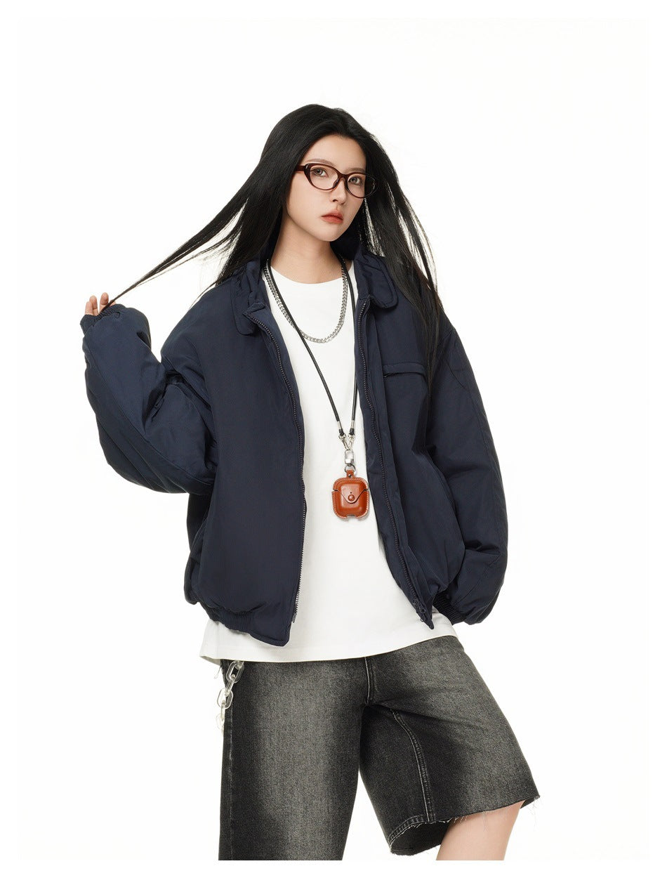 Model wearing an open oversized navy jacket with a collar and chest pocket, paired with a white shirt and dark shorts.