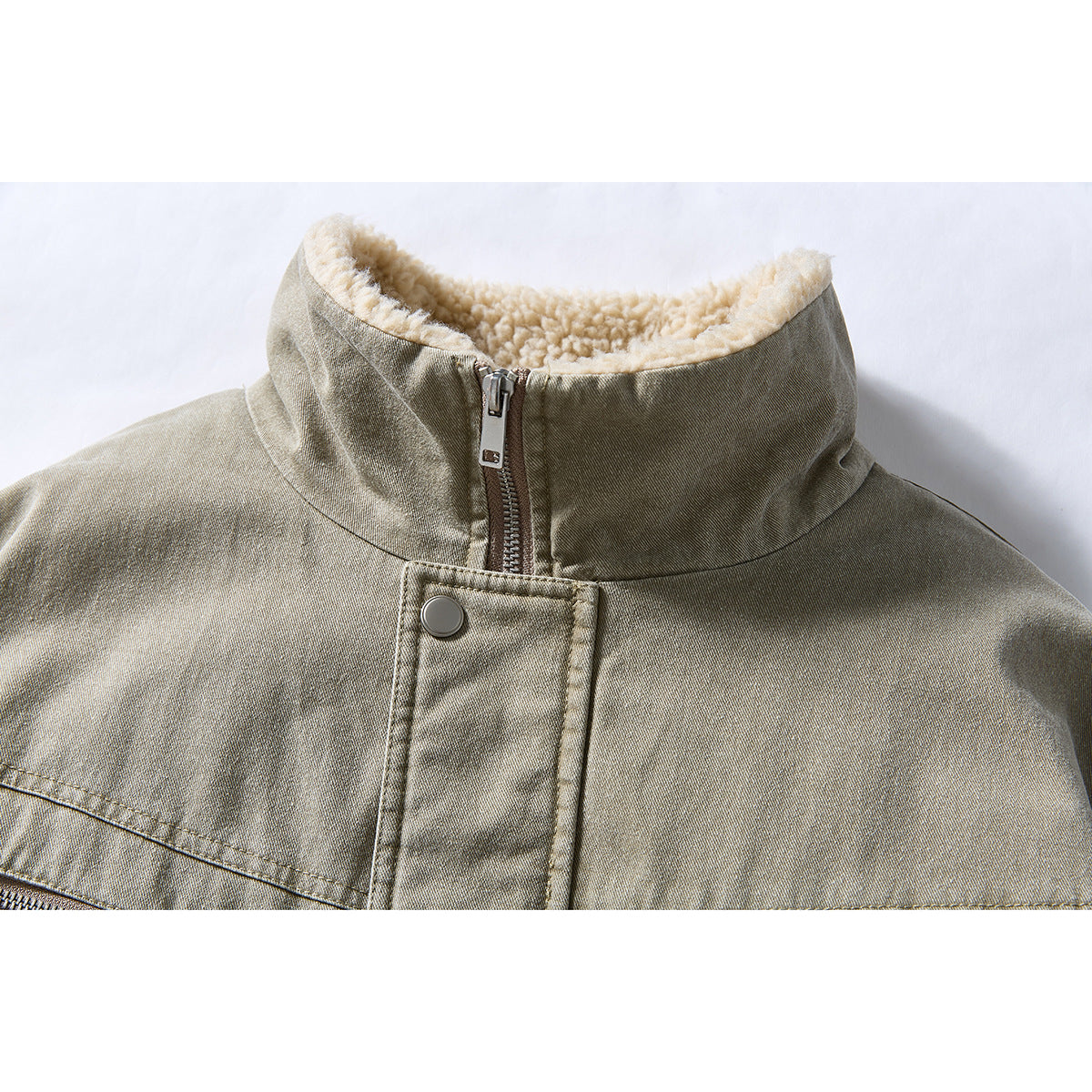 Close-up of an olive-gray jacket’s cream sherpa-lined collar, front zipper, and snap-button placket.