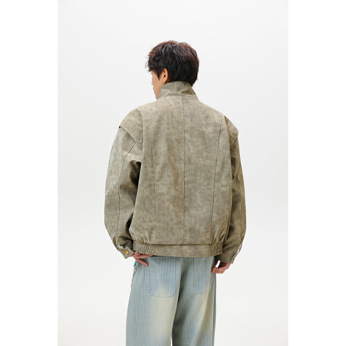 Back view of a model wearing the taupe jacket, showing its panel seams and elasticized hem.
