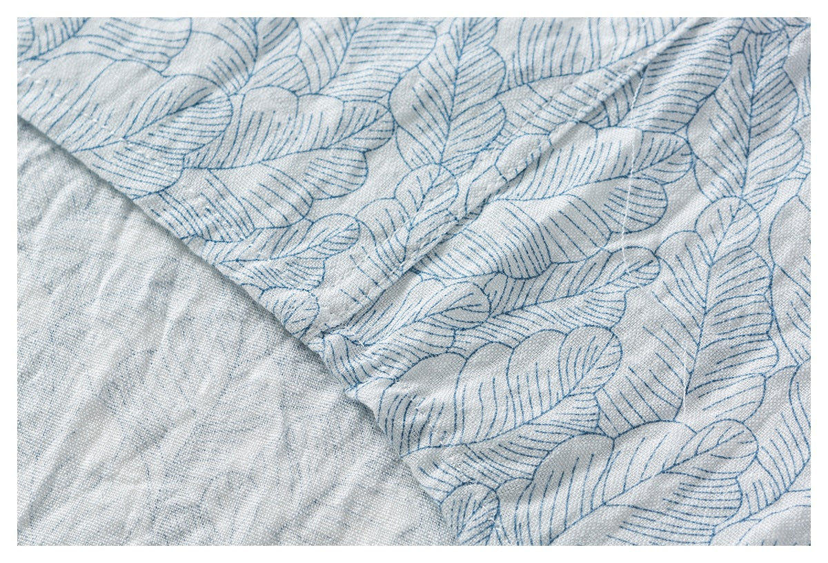 Close-up of blue leaf-print fabric folded back to show its plain, lightly textured reverse.