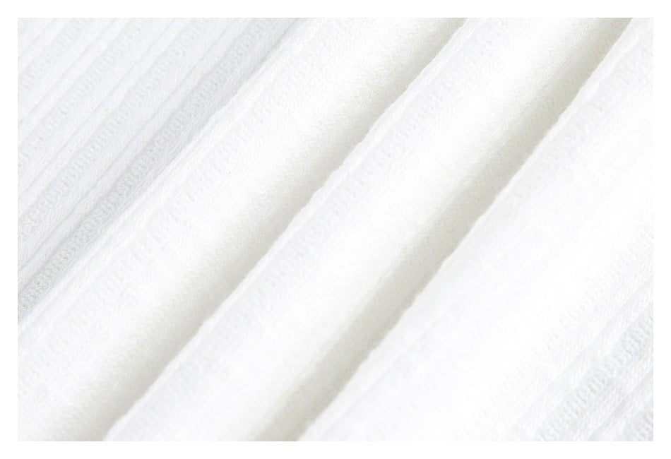 Extreme close-up of white knit fabric with raised bands and a soft folded seam.