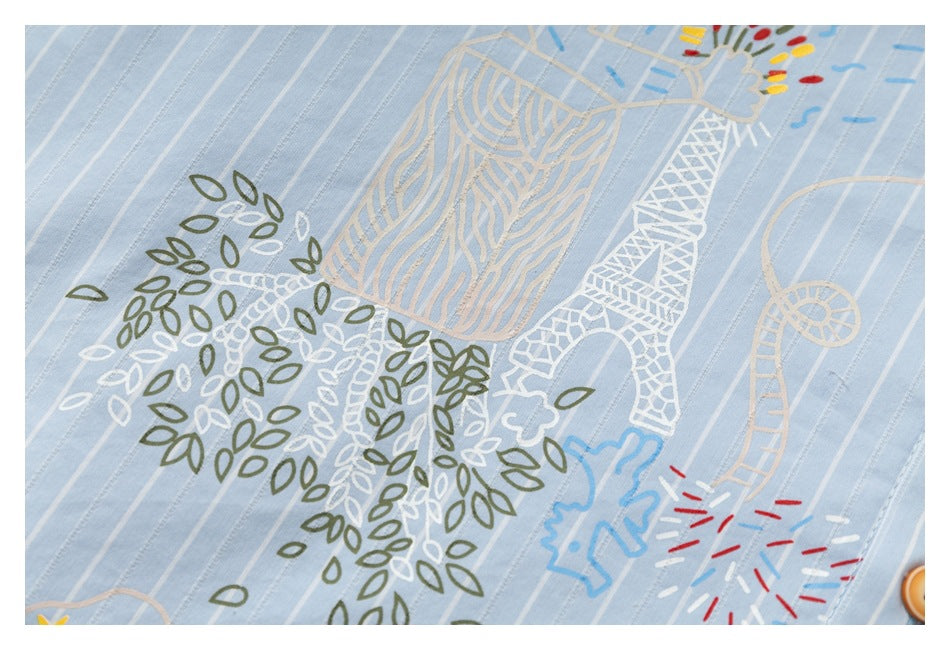 Close-up of light blue pinstriped fabric with colorful line-art motifs, including leaves and whimsical figures.