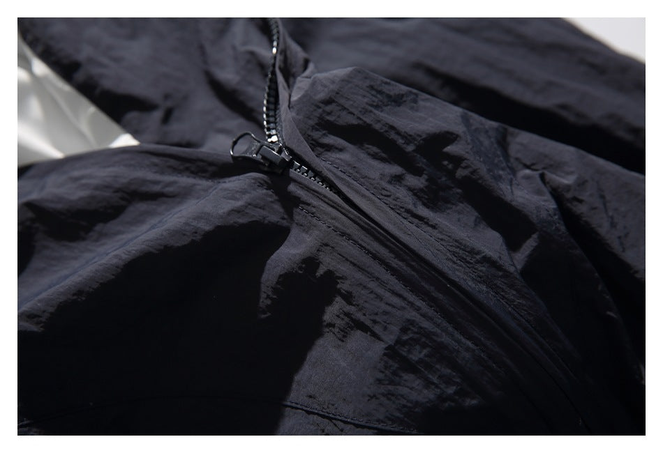 Close-up of a black garment with a diagonal zipper and textured fabric.
