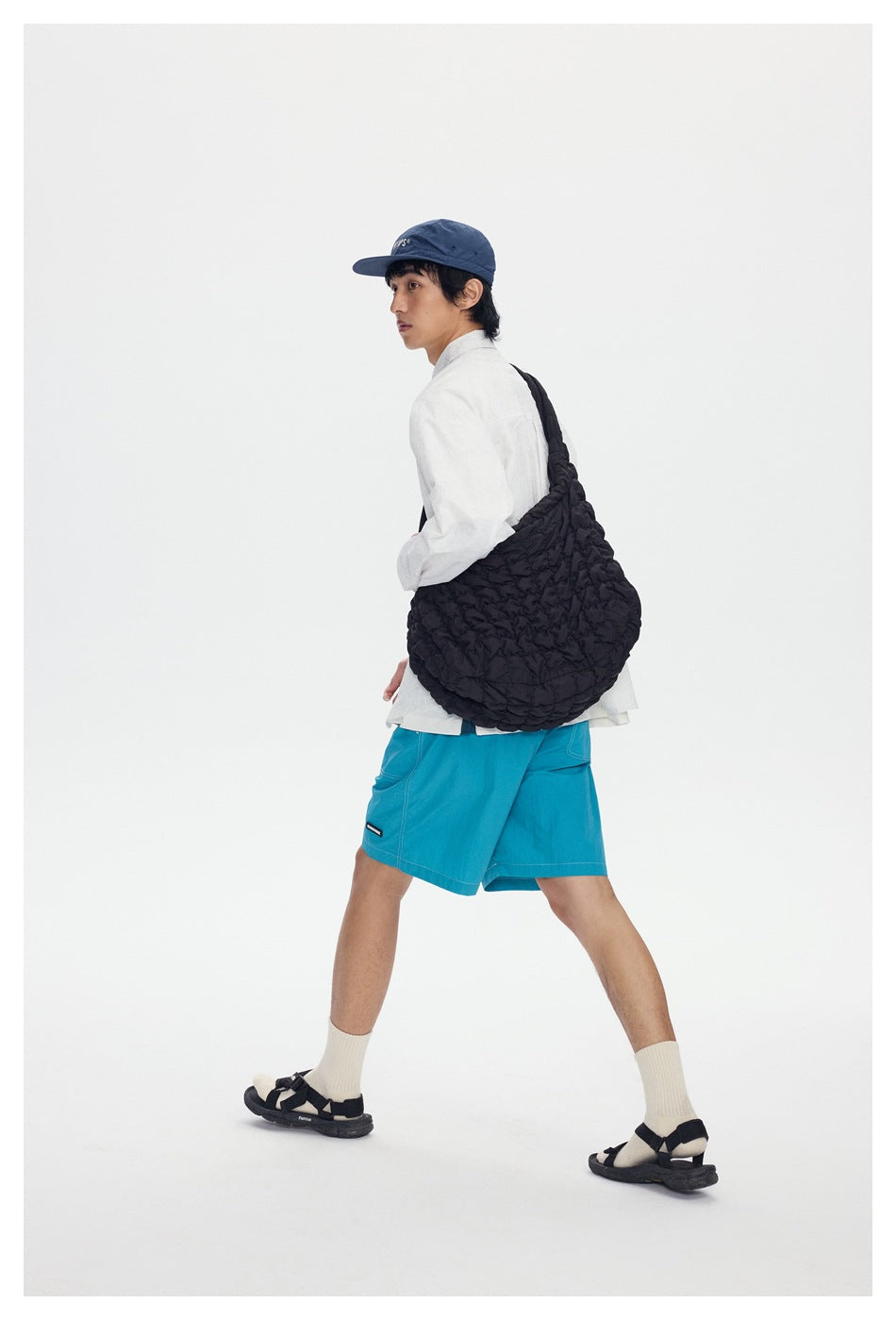 Walking model shown from behind in bright turquoise shorts with patch pockets and contrast stitching.