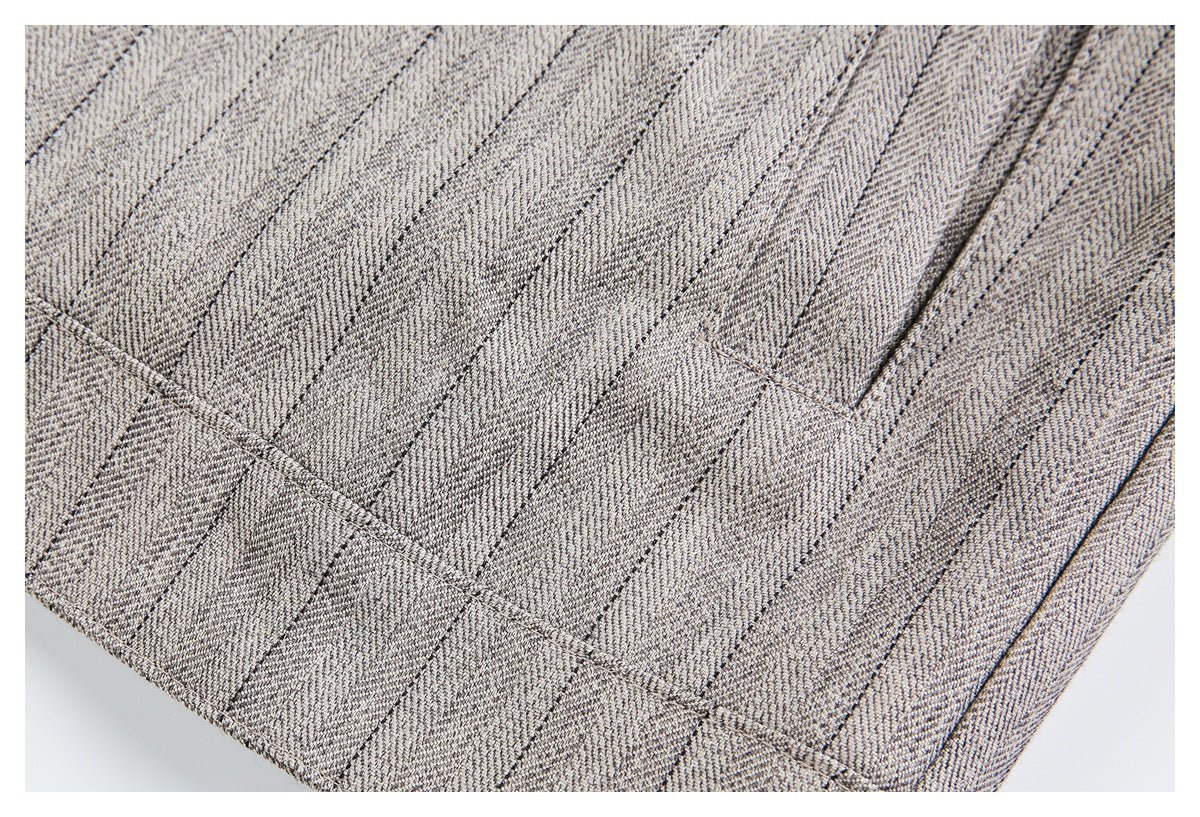 Close-up of gray-beige patterned fabric with intersecting stitched seams and a folded edge.