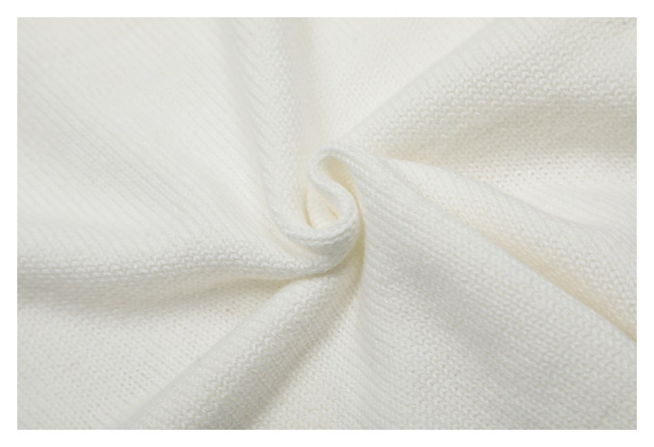 Close-up of soft-looking ivory knit fabric gathered into folds, showing its stitch texture.