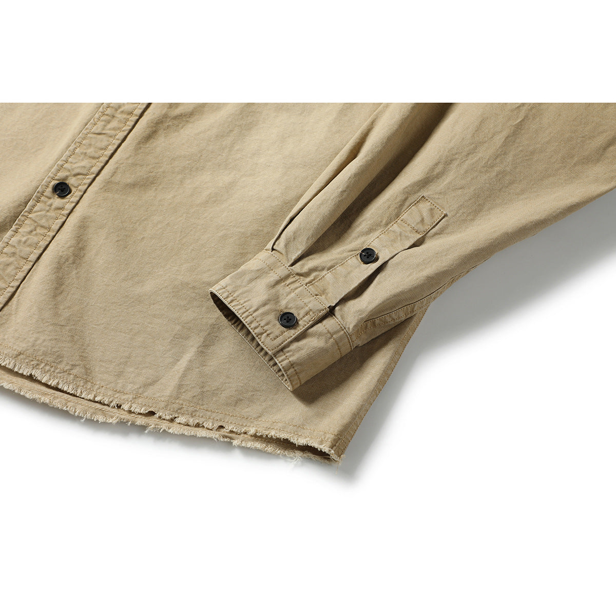 Close-up of a tan shirt sleeve with buttoned cuff and a frayed hem.
