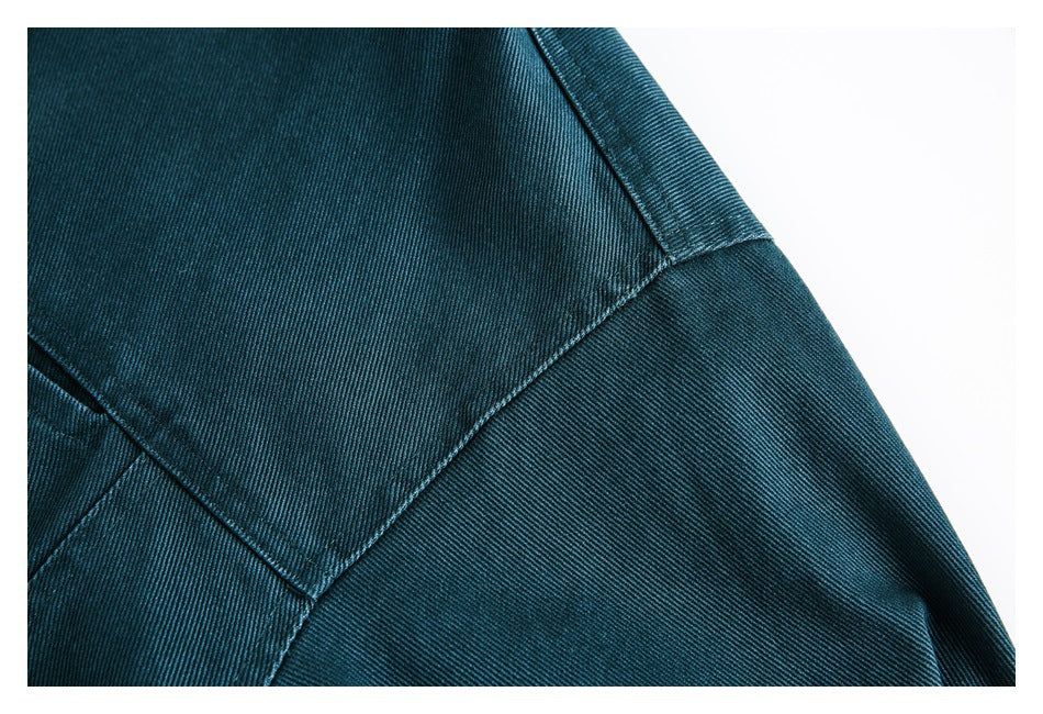 Close-up of diagonal stitched seams and a garment edge in teal twill.