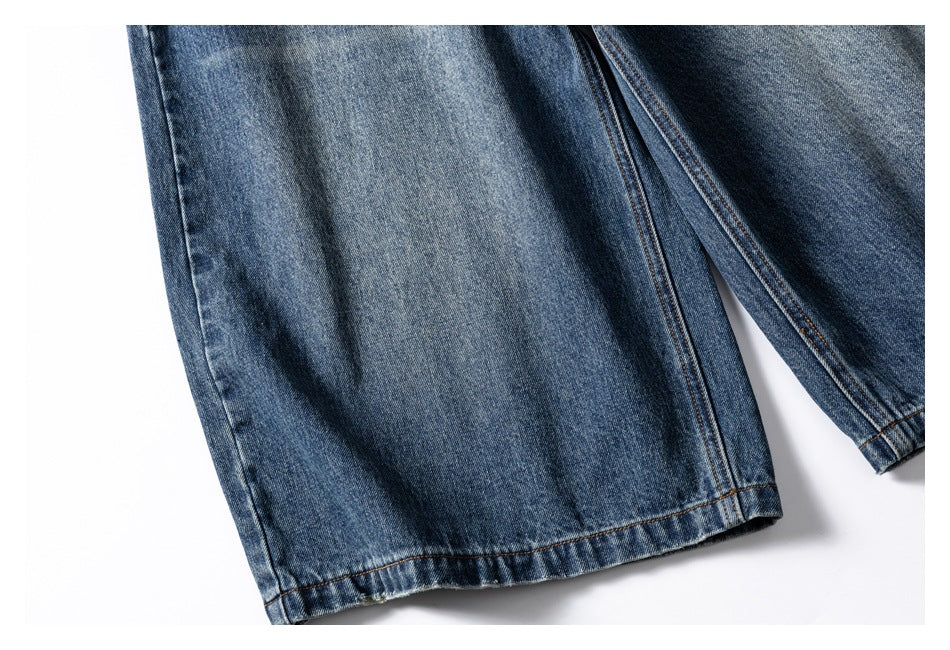 Close-up of blue denim jean legs and stitched hems on a white background.
