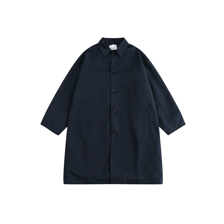 Navy mid-length button-front coat with pointed collar and slit pockets, laid flat on a white background