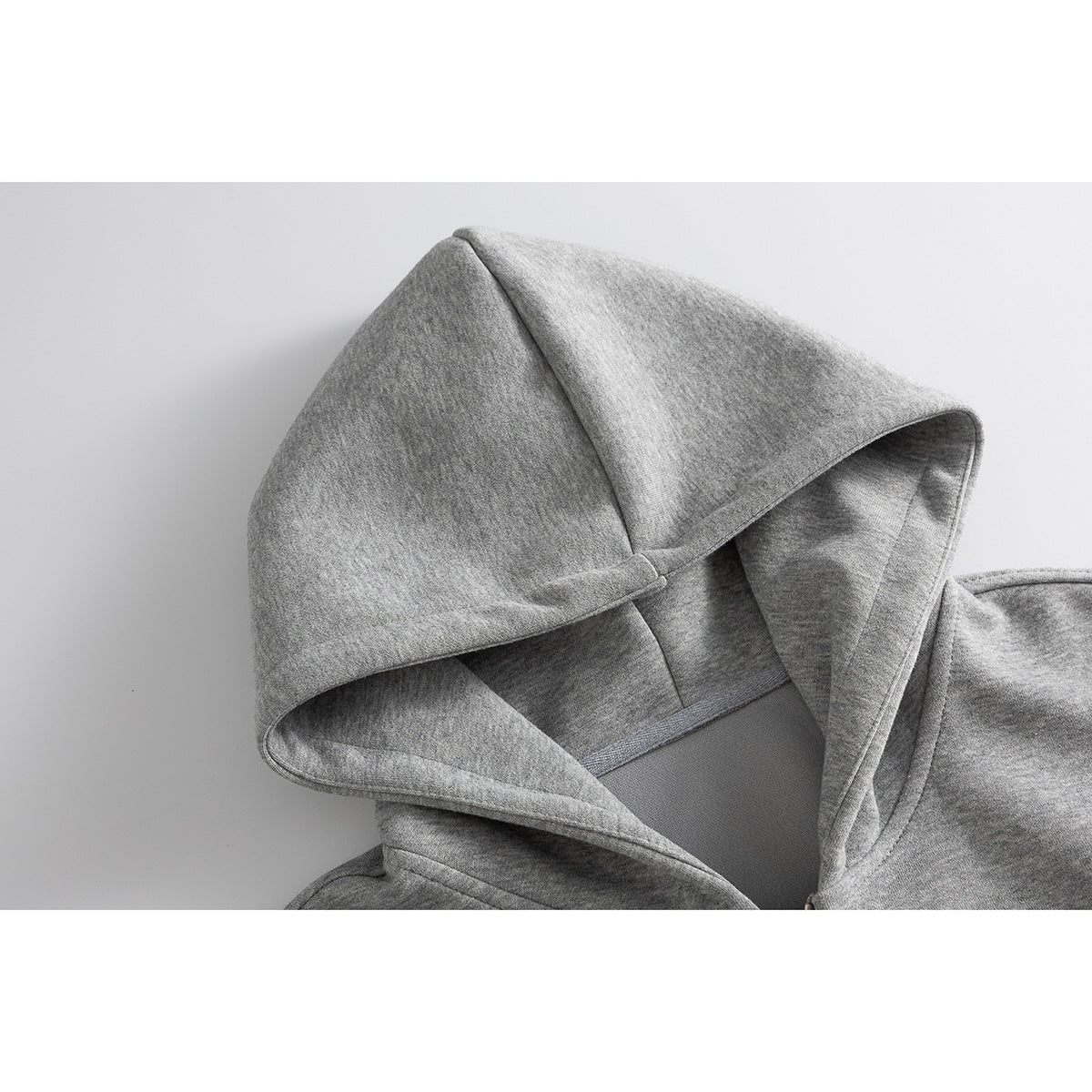 Close-up of a gray zip-up hoodie showing the hood’s interior and seams.