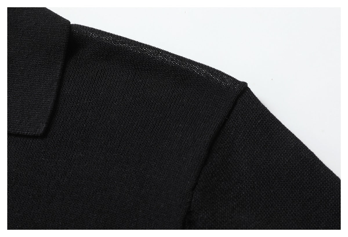 Close-up of the black knit polo's shoulder and short sleeve, showing the fabric texture and seam.