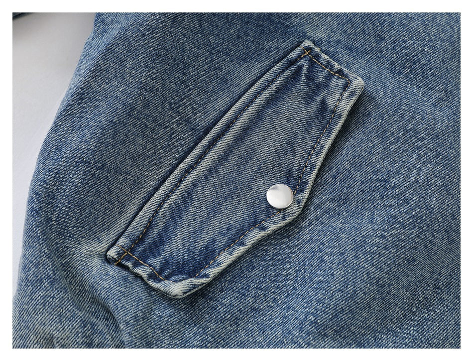 Close-up of a blue denim jacket pocket flap secured with a silver snap button.