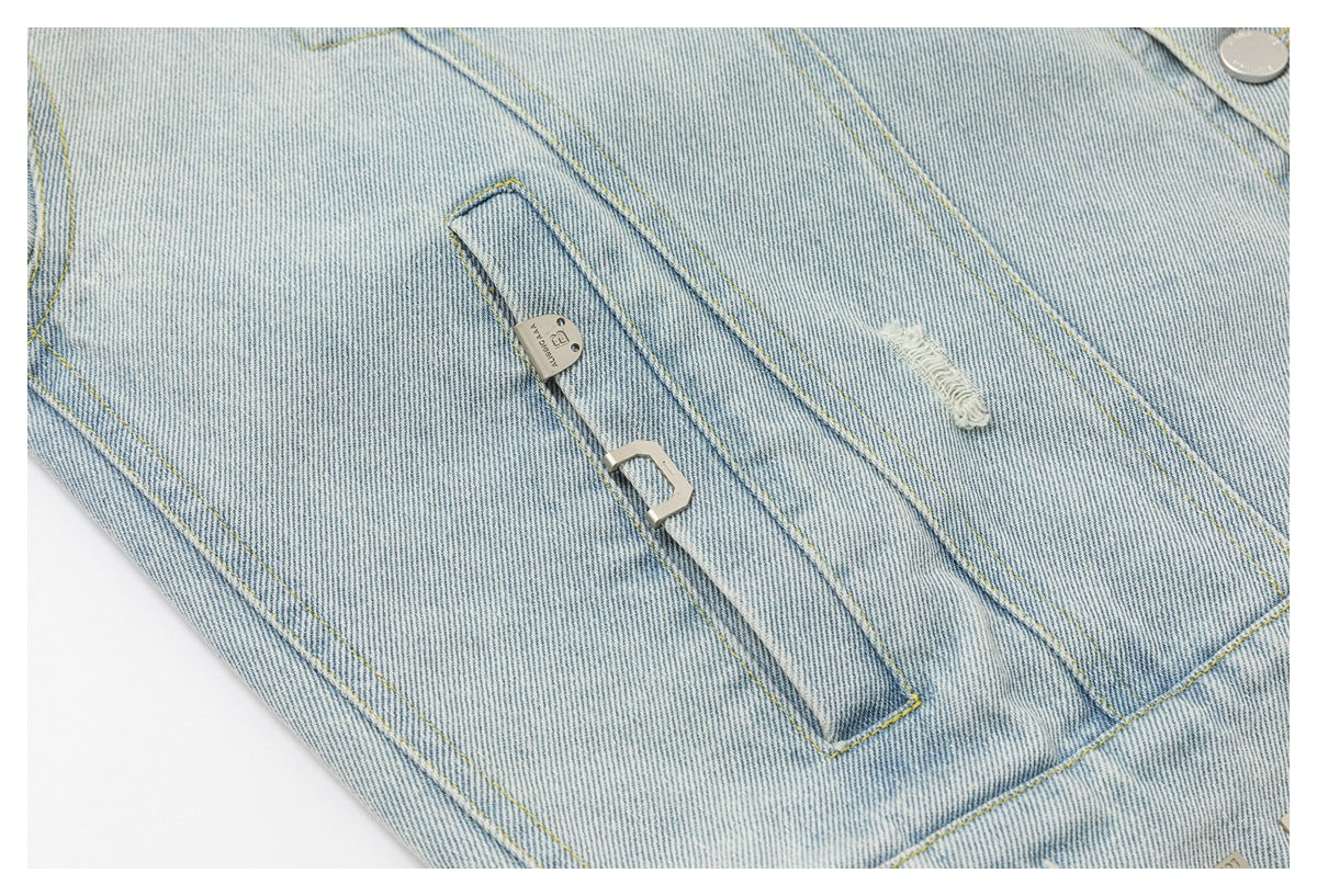 Close-up of a pale blue denim jacket front with a zip pocket, distressed spot, and silver-tone hardware.