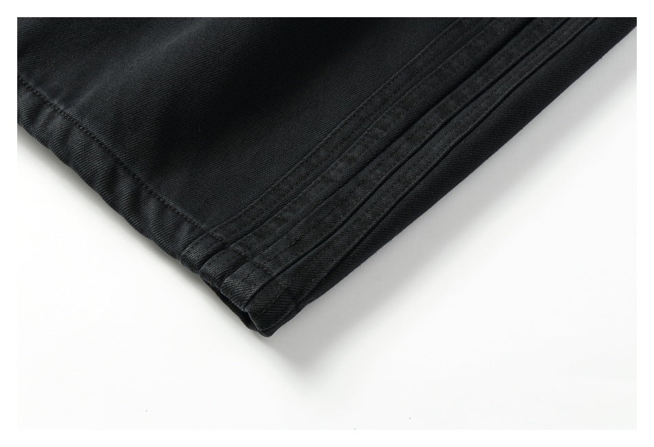 Close-up of the stitched hem and fabric edge of a black pants leg.