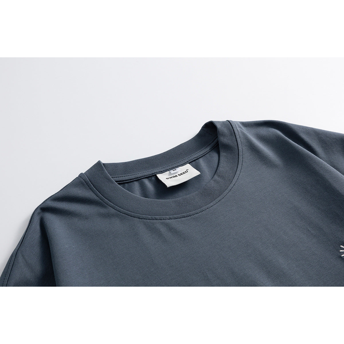 Close-up of a dark slate blue T-shirt’s ribbed crew neck and inner label.