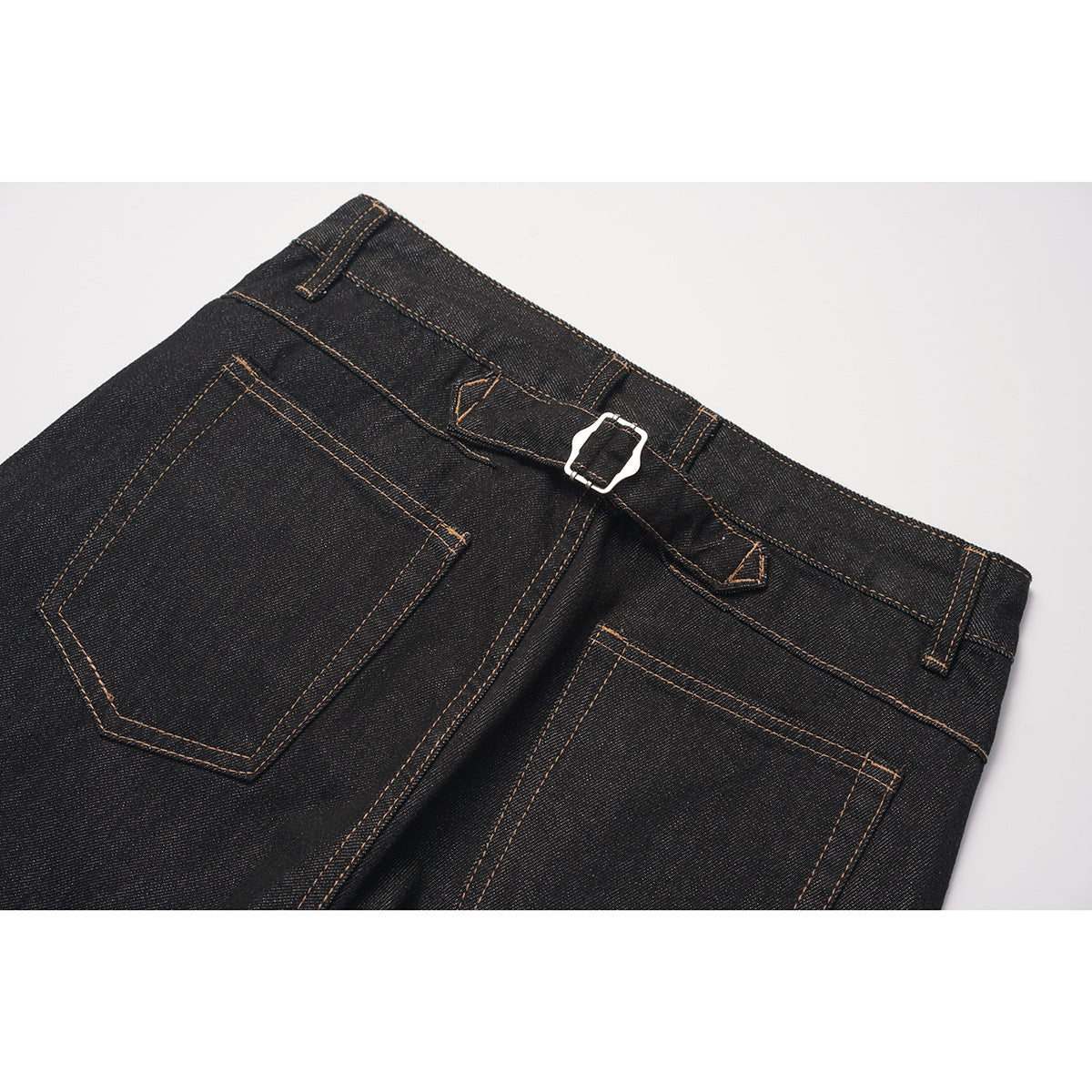 Close-up of the back of black jeans, showing two pockets, a buckle detail, belt loops, and contrast stitching.