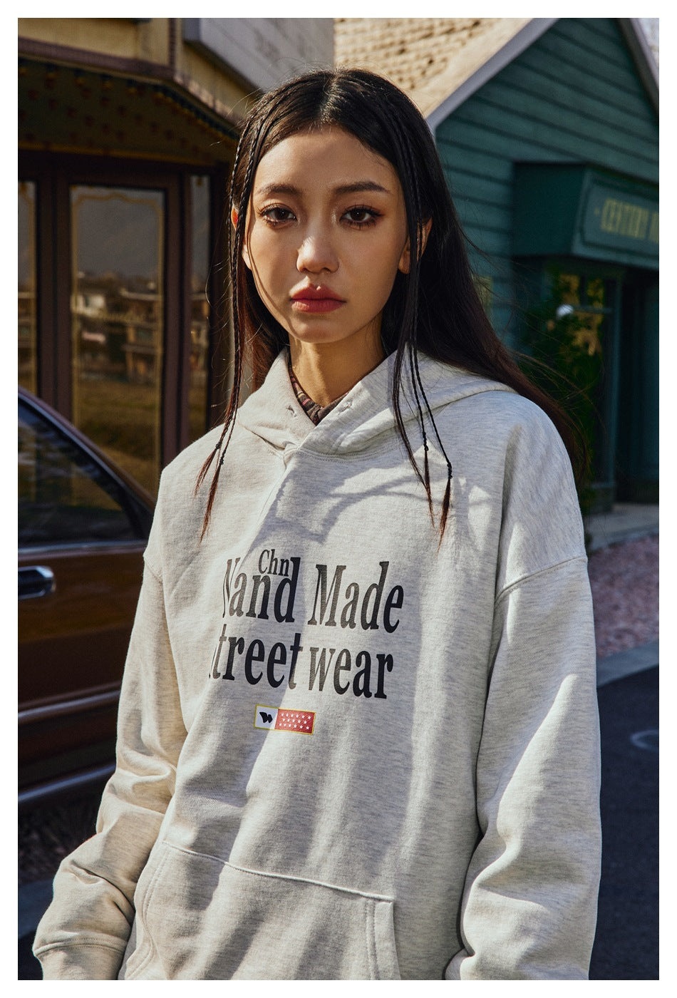 A woman models a light gray “Hand Made Street wear” pullover hoodie with a front pouch pocket.