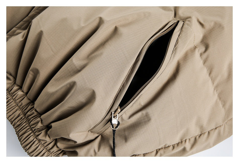 Beige padded garment close-up showing an open diagonal zip pocket and gathered elastic hem.