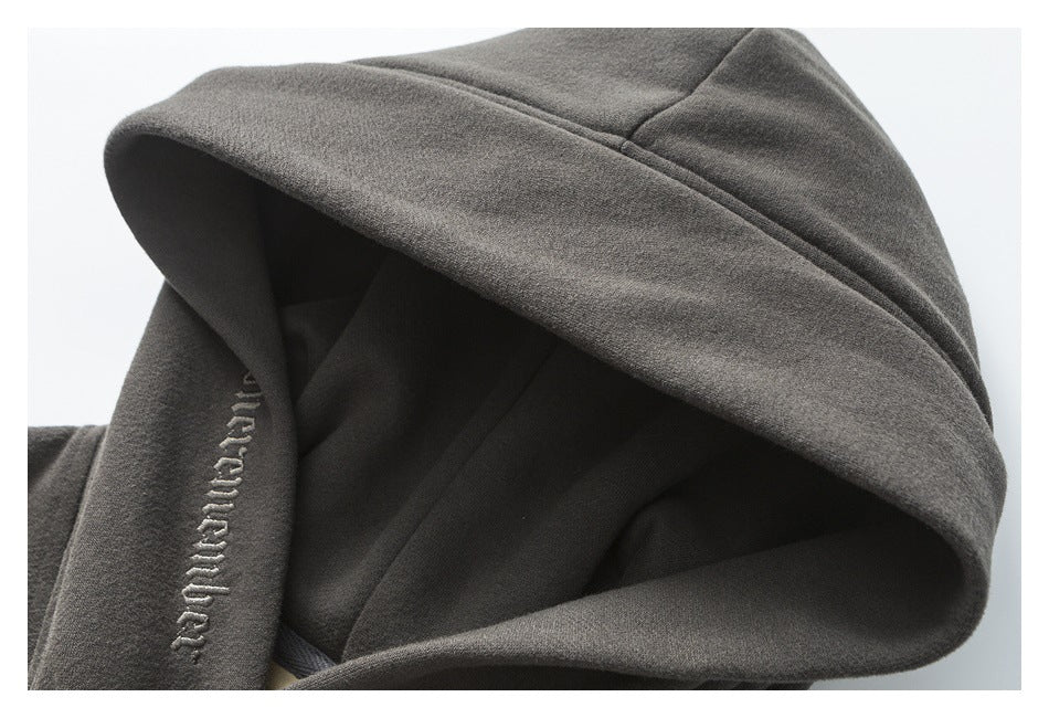 Close-up of a charcoal hoodie’s large hood and embroidered lettering on its edge.