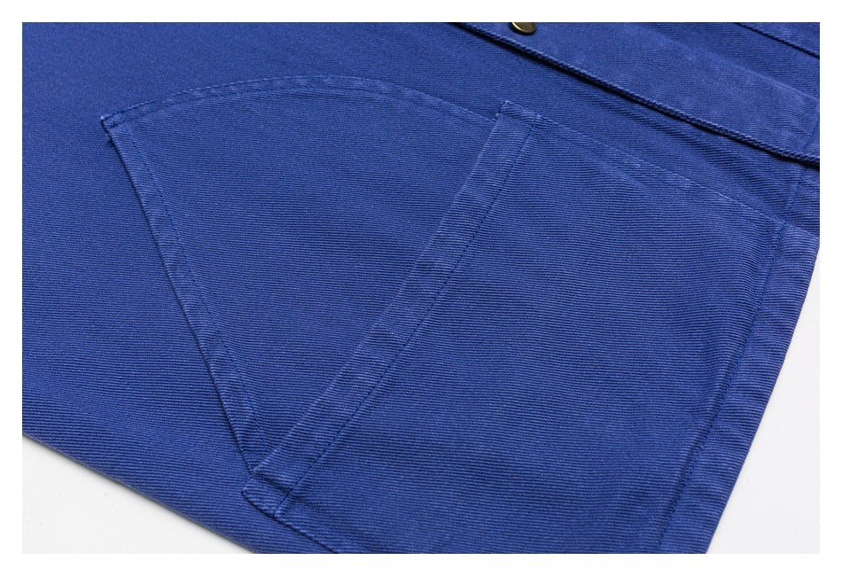 Close-up of a blue garment pocket with angled seams and a small brass-colored button.