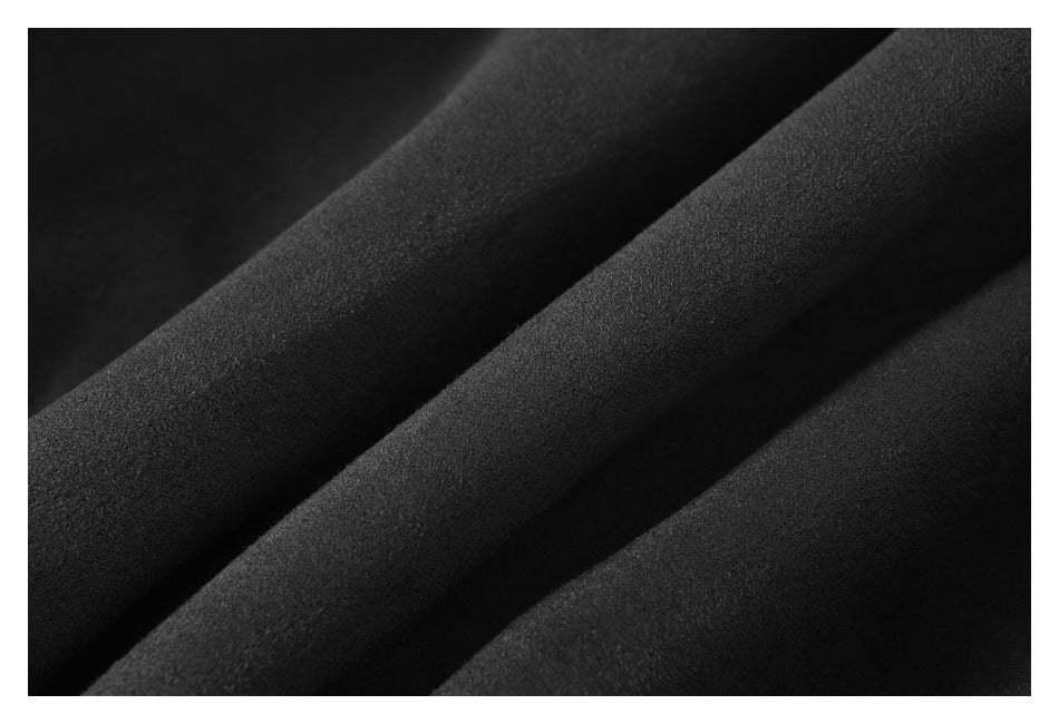 Extreme close-up of dark fabric arranged in soft folds, showing its surface texture.