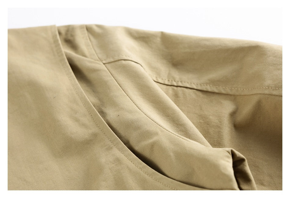 Close-up of a curved pocket opening and stitched seams on beige fabric.