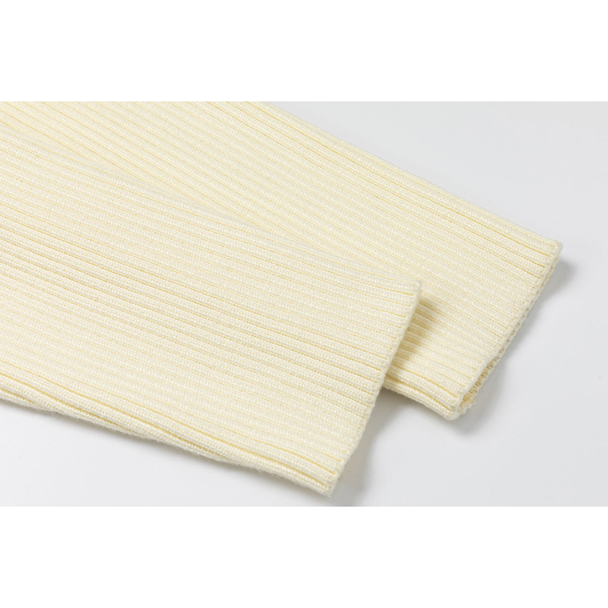 Close-up of the ivory jacket's ribbed knit sleeve and cuff.