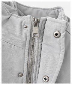 Close-up of the light gray jacket's front zipper, snap-fastening storm flap, and stand collar.
