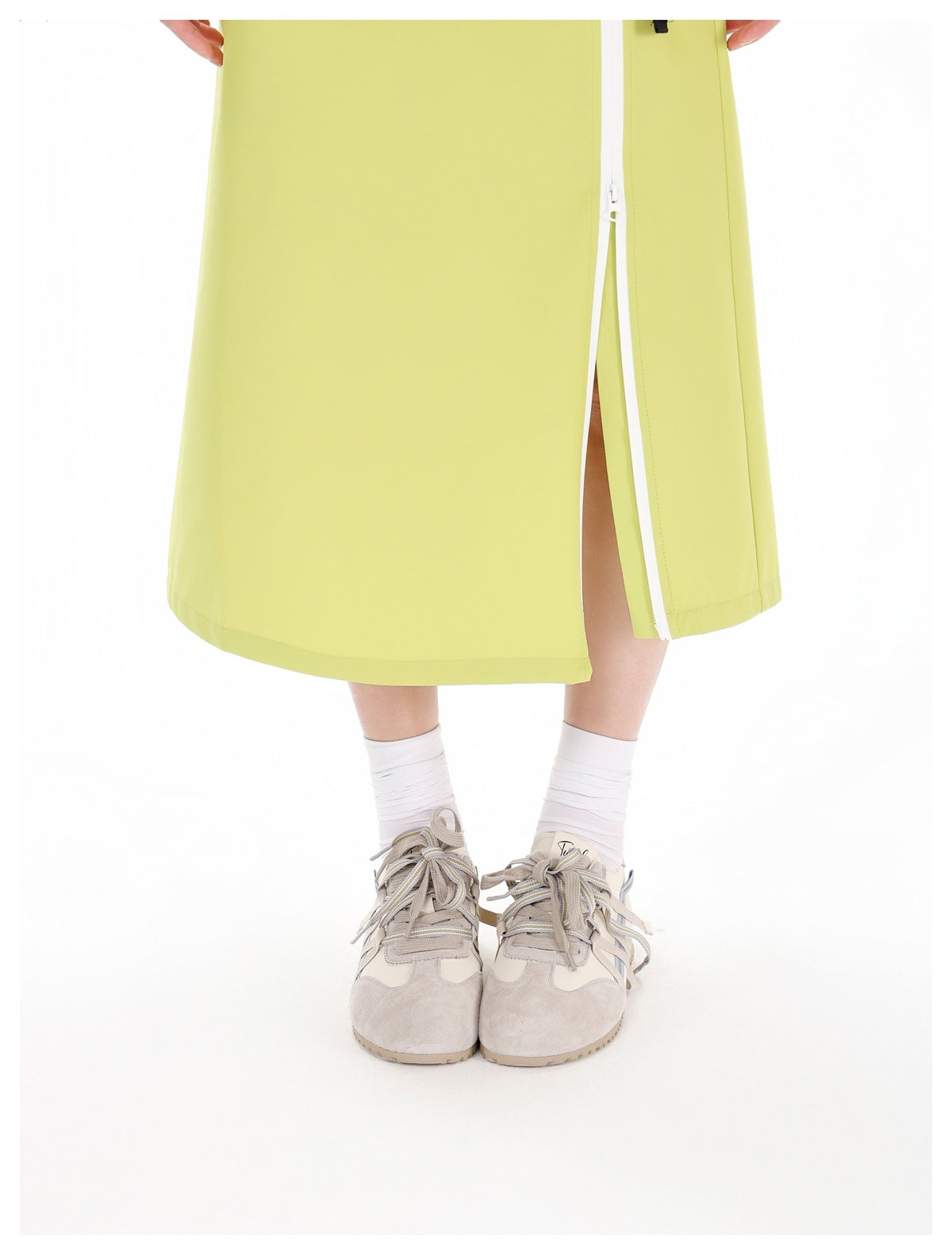 Close-up of the lime-green skirt hem and white zipper, shown partly open to reveal the slit.