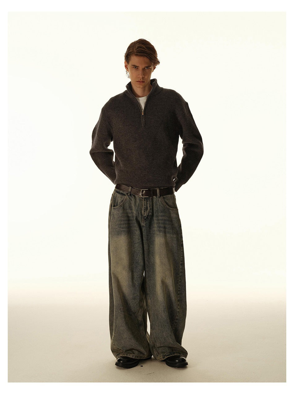 Front full-length view of a model wearing a dark charcoal-brown ribbed quarter-zip sweater with oversized washed gray jeans.