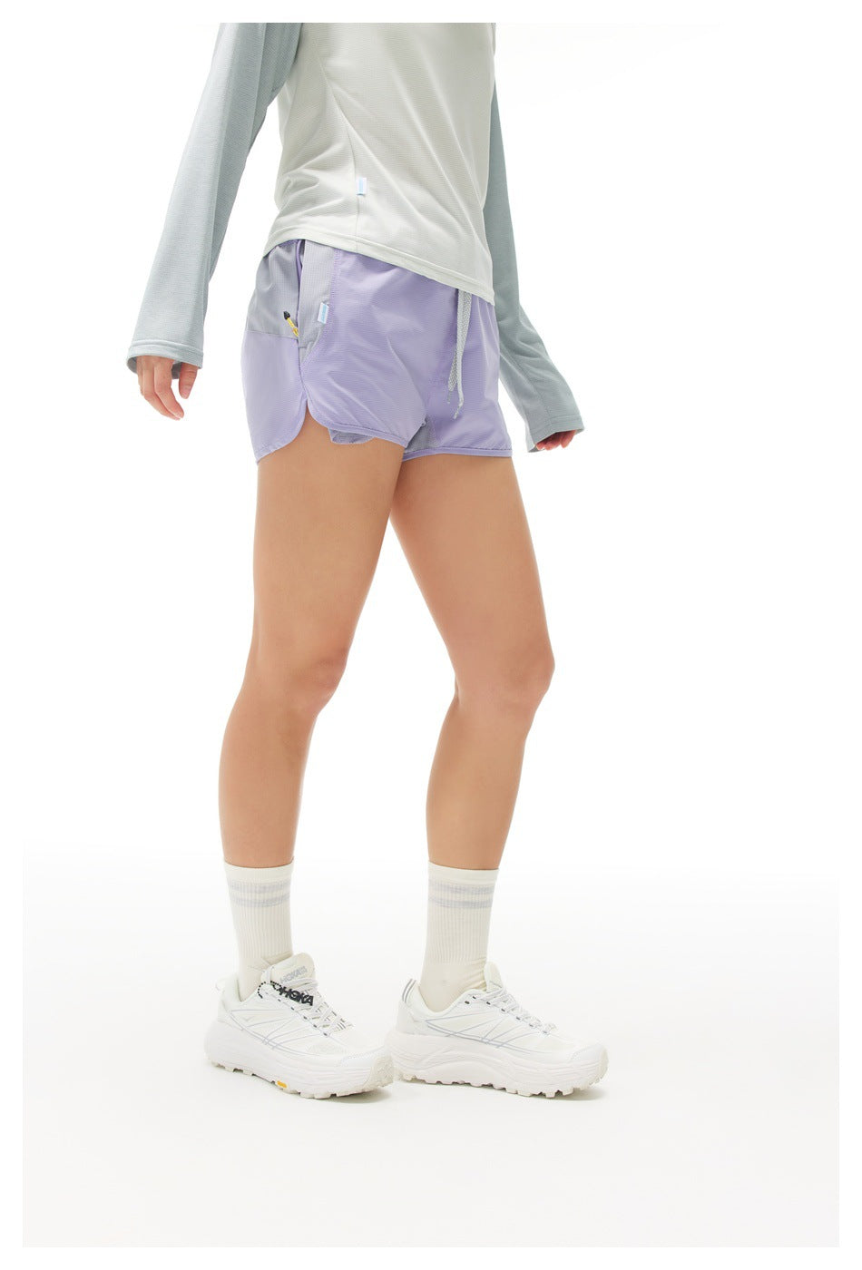 Side view of a model wearing lavender running shorts with a gray pocket panel and drawstring waist.