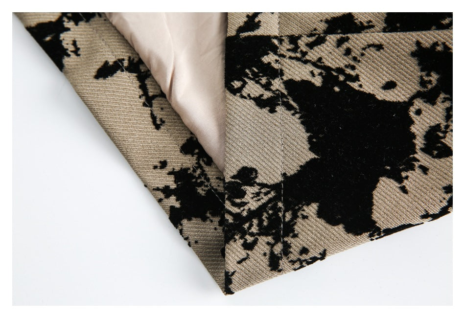 Folded edge of tan and black patterned fabric reveals a pale lining and stitched seam.