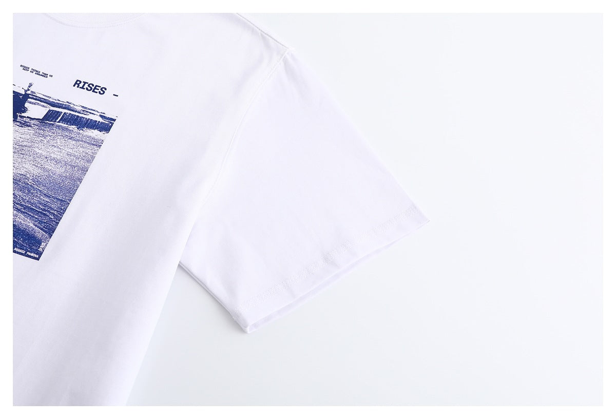 Close-up of the white T-shirt's short sleeve, hem stitching, and part of its navy chest graphic.