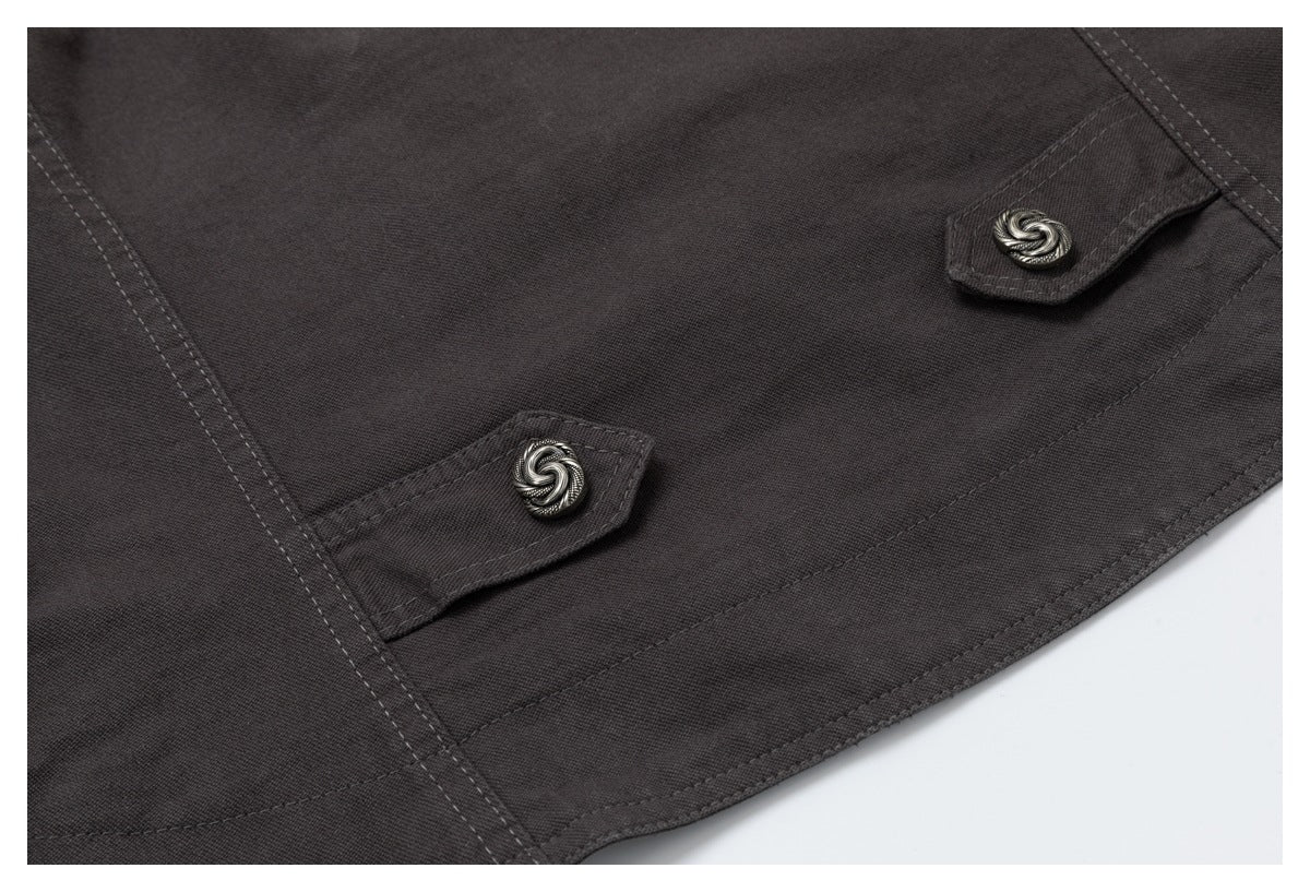 Dark charcoal jacket detail showing two fabric tabs with silver-tone buttons and curved stitching.