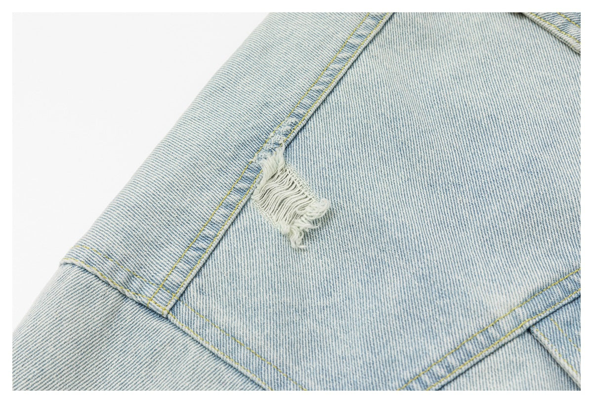 Close-up of a frayed distressed patch along a seam on light-wash denim.