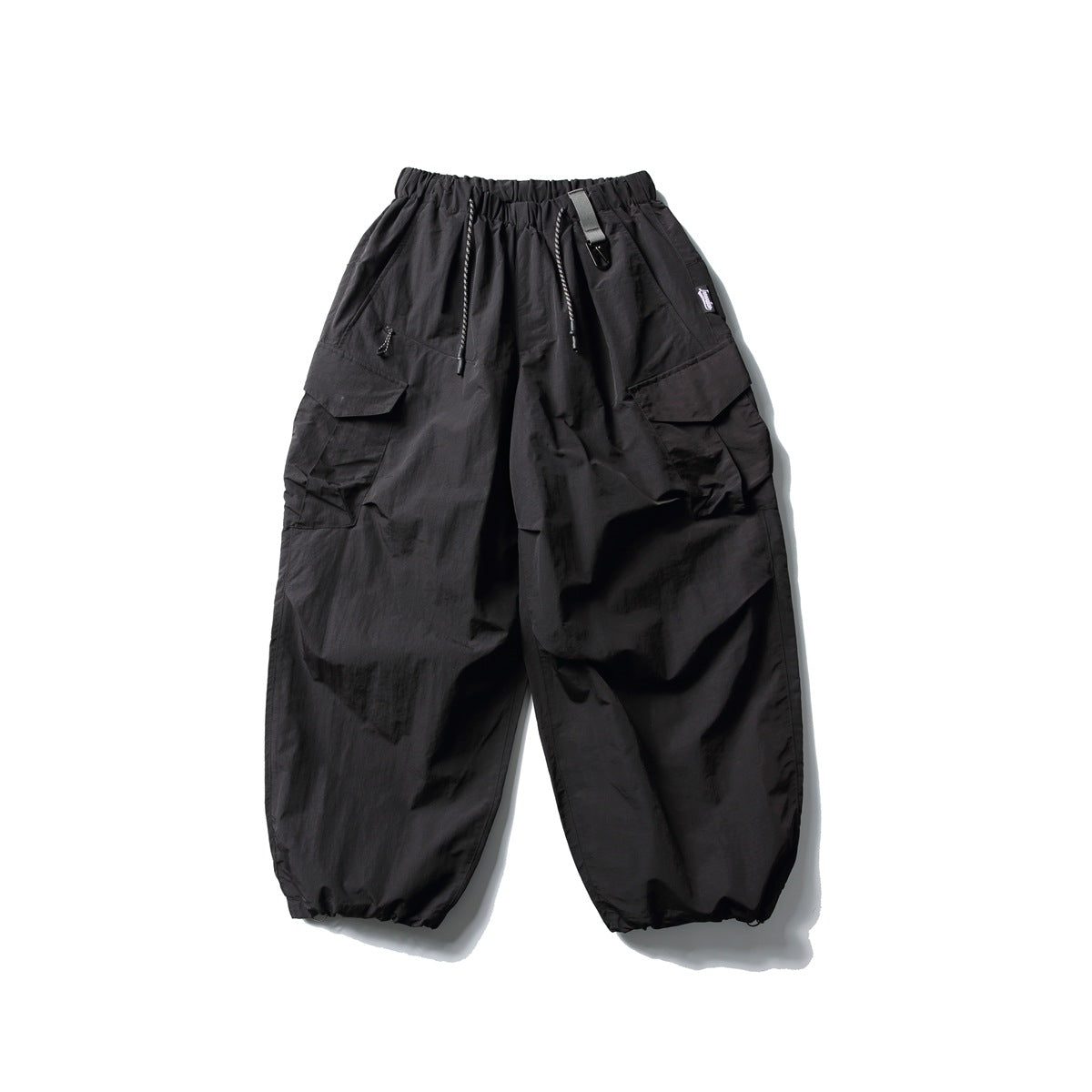 Black oversized cargo pants with an elastic drawstring waist, large flap pockets and gathered ankle cuffs.