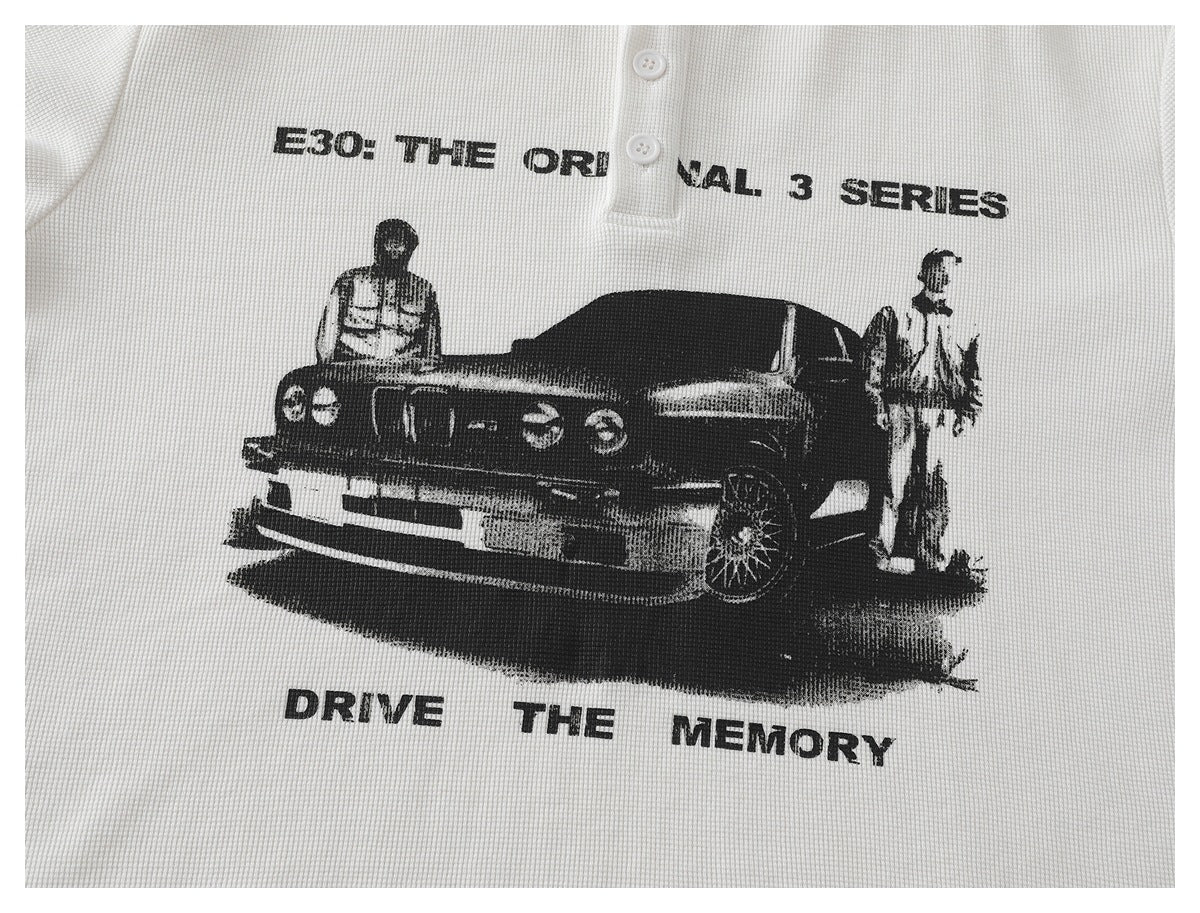 White waffle-knit shirt with a black car-and-figures graphic and English lettering across the chest.