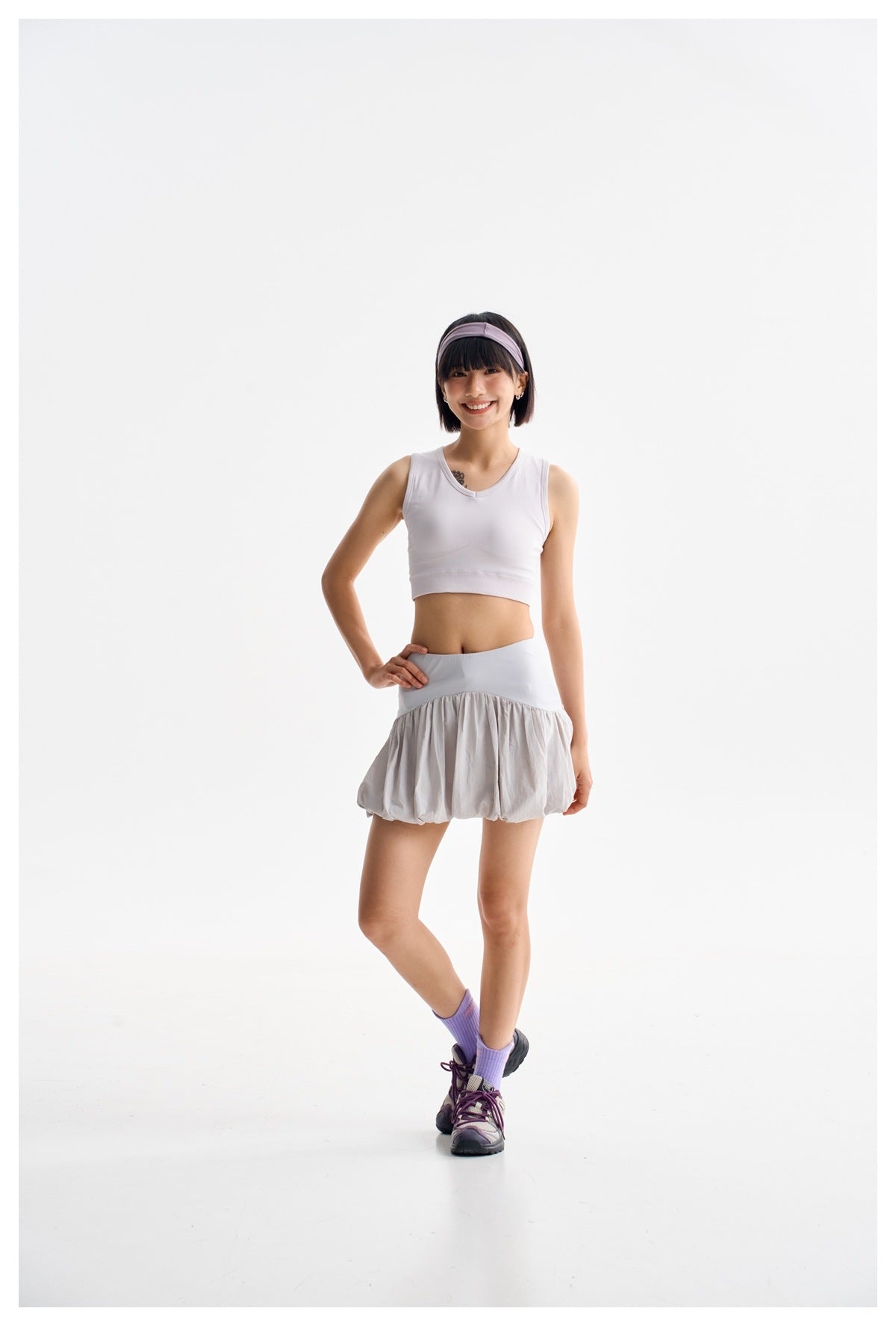 Full-length front view of a model wearing a light gray bubble-hem skirt and white cropped top.