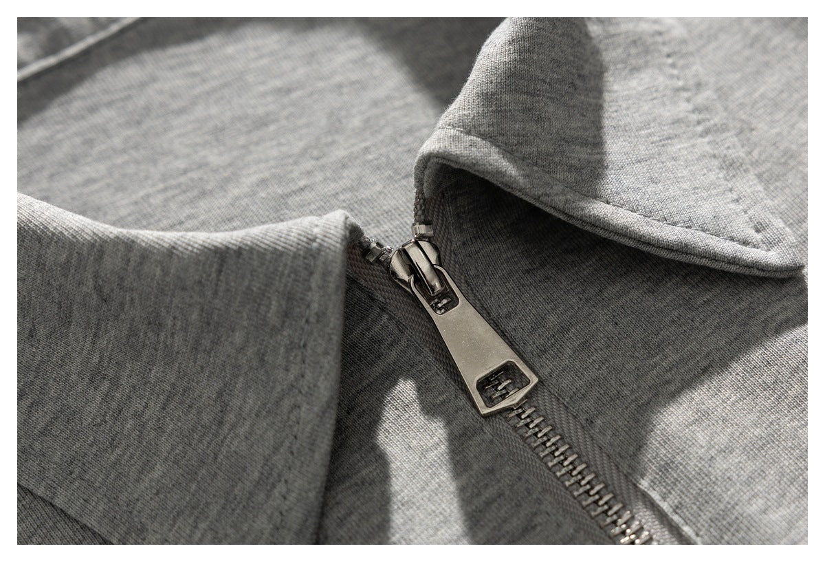 Close-up of the gray garment's metal zipper pull beside its folded collar.