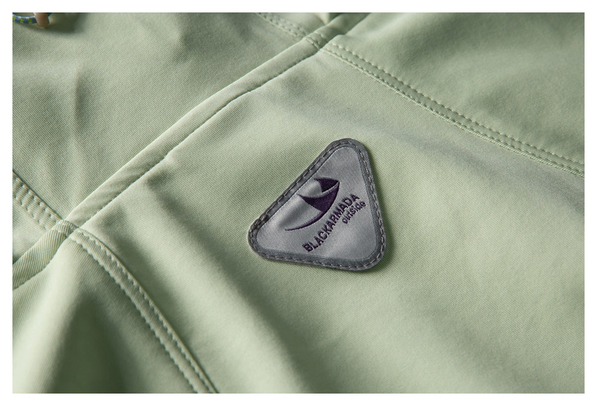 Close-up of a triangular branded patch sewn onto pale green fabric.