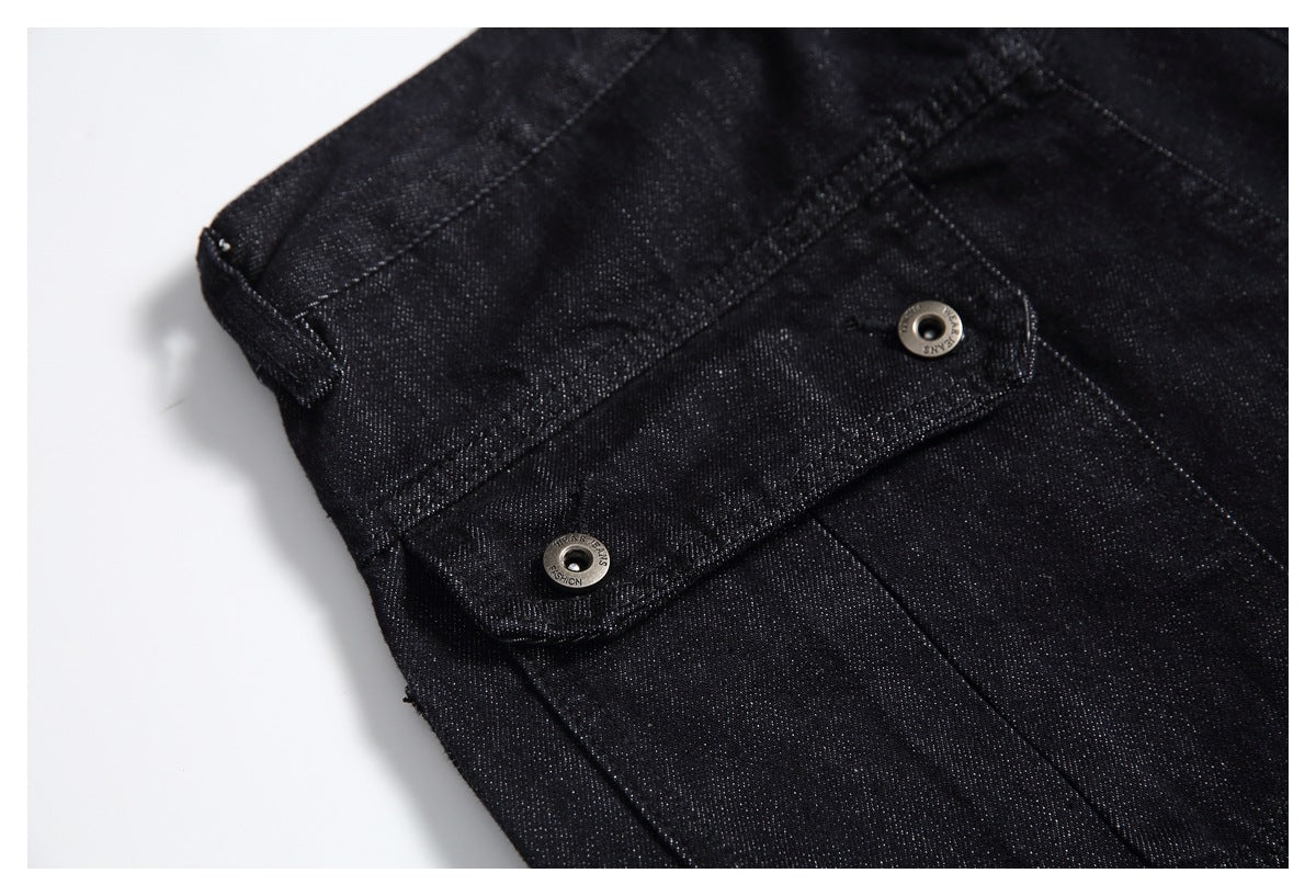 Close-up of black denim flap pocket with two metal snap buttons and visible stitching.