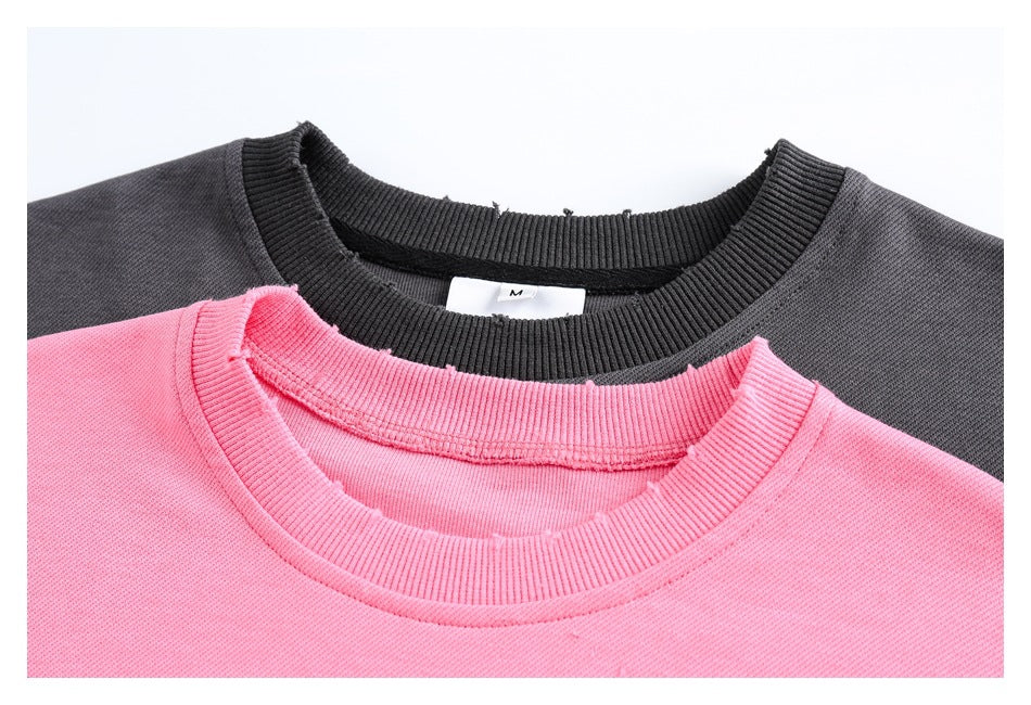 Close-up of pink and charcoal crewneck sweatshirts showing their ribbed collars and a small M size tag.