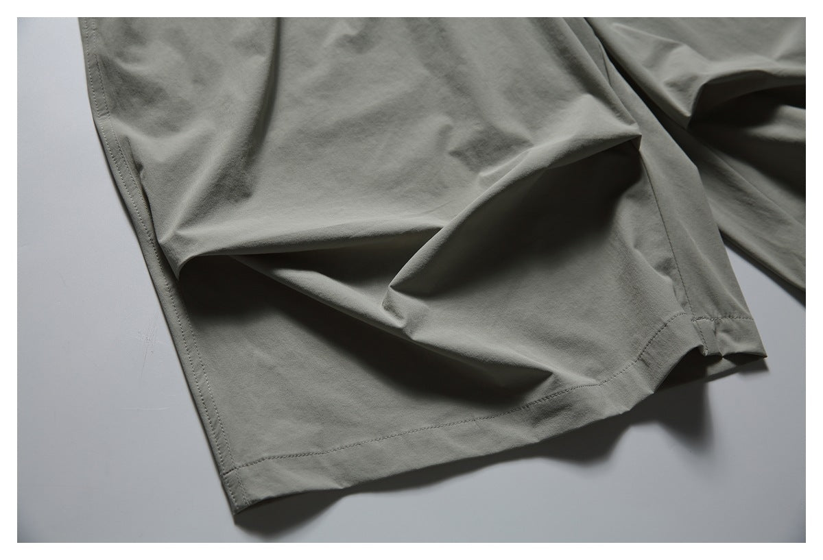Close-up of a gray-green shorts leg showing the folded hem and stitching.