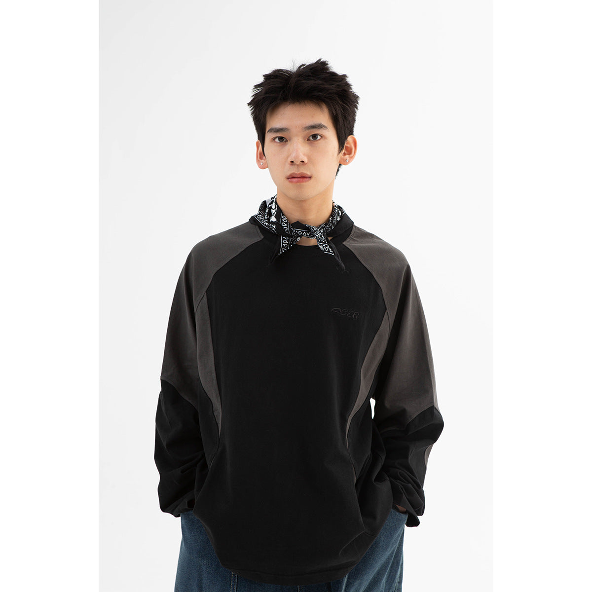 Front view of a model wearing an oversized black sweatshirt with charcoal gray raglan panels.