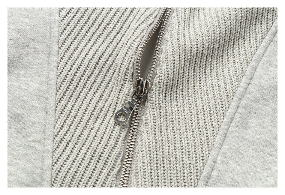 Close-up of a silver zipper on a light heather-gray garment with a textured knit panel.
